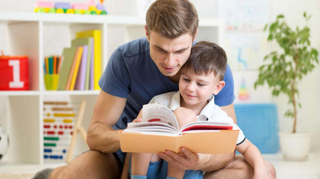 Ребенок читает книгу с родителем